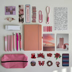 Collection of stationery items including a notebook, pens, and stickers on a light background