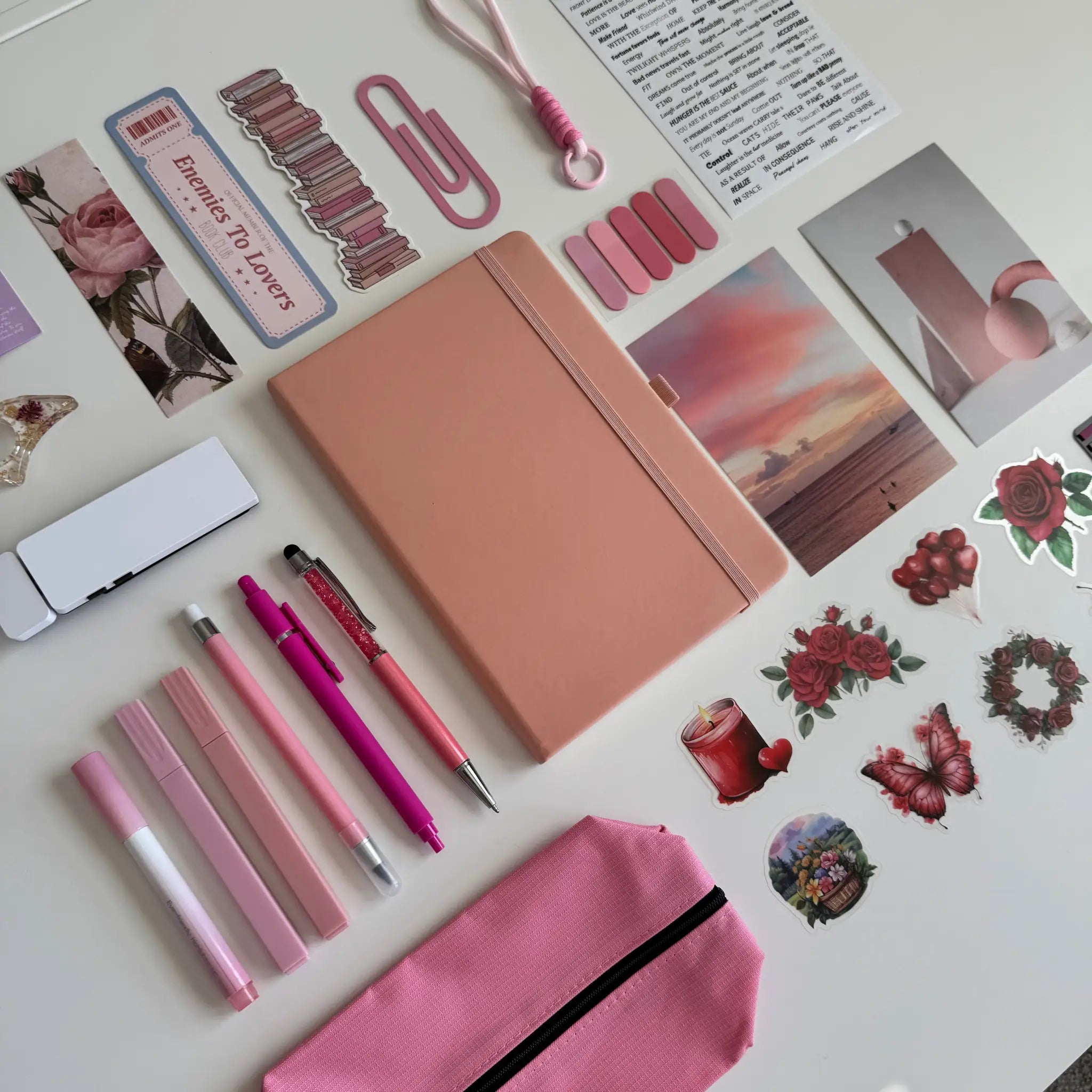Collection of stationery items including a notebook, pens, and stickers on a light surface.