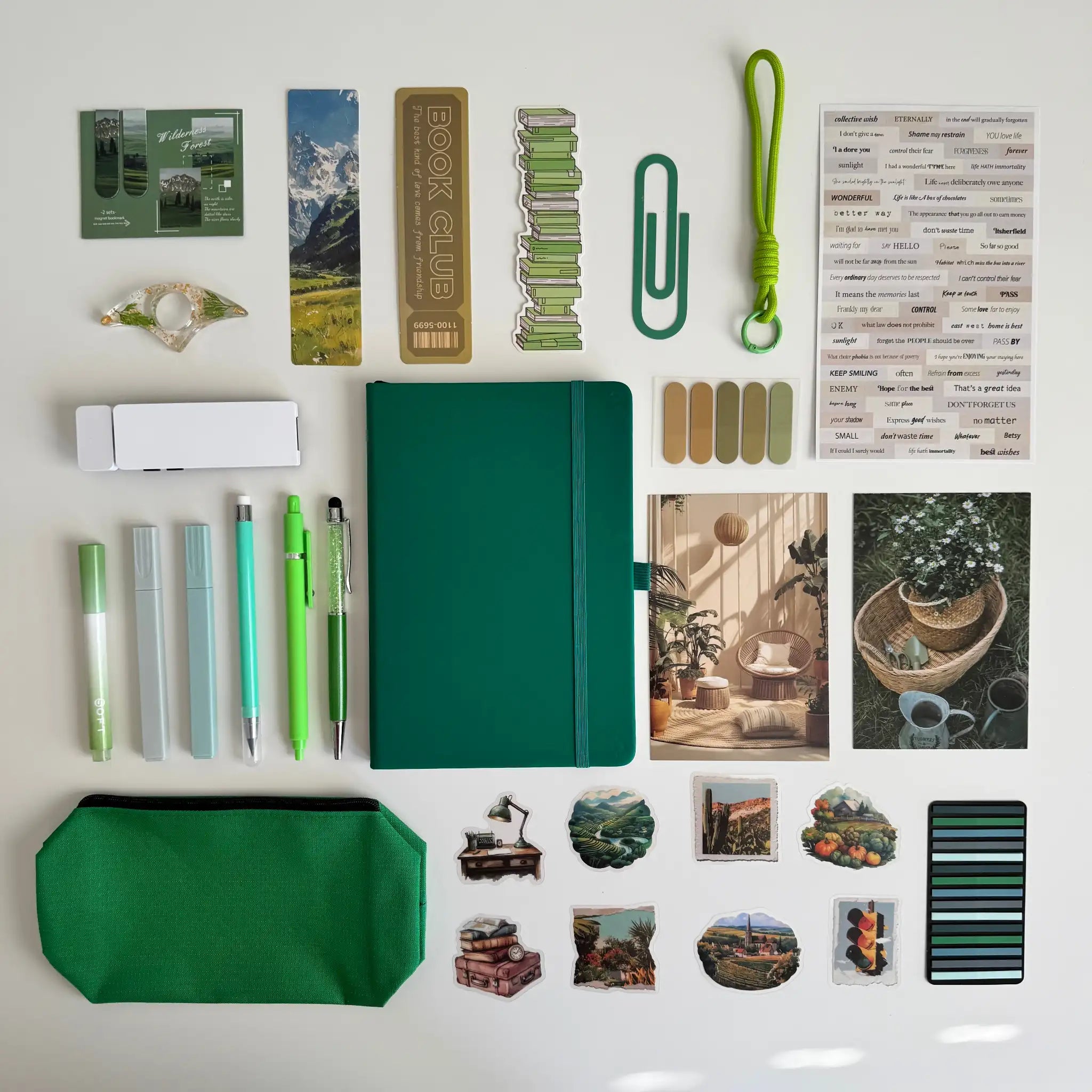Collection of stationery items including a green notebook, pens, markers, and stickers on a white background.