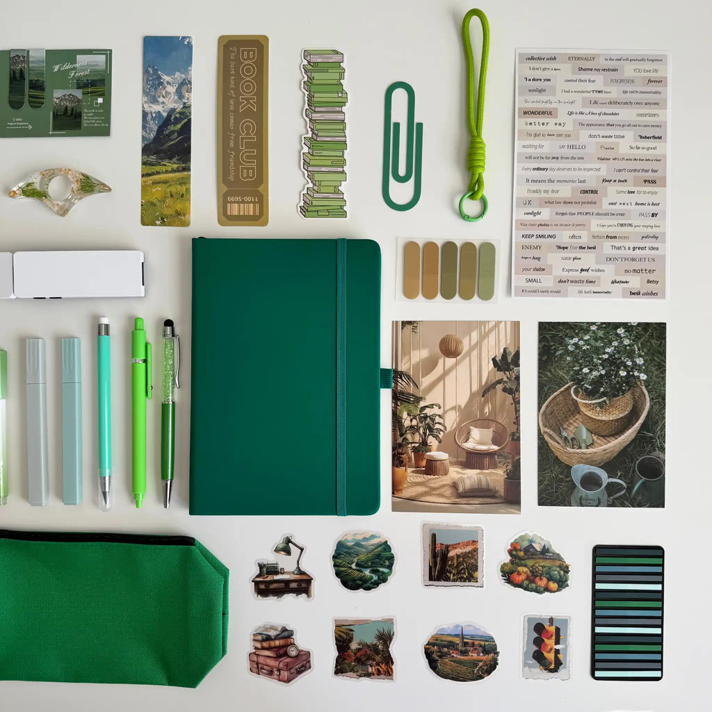 Collection of stationery items including a green notebook, pens, and decorative stickers on a white background.