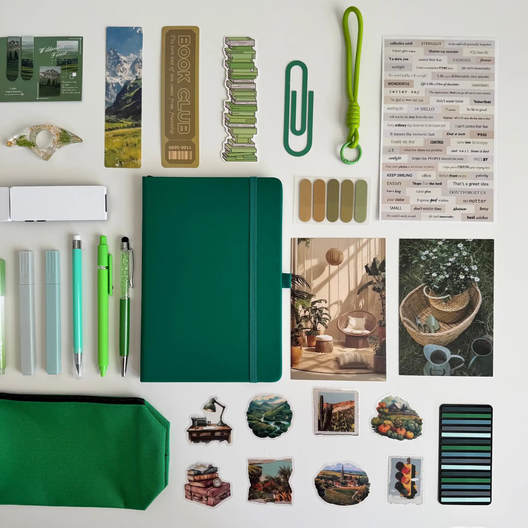 Collection of stationery items including a green notebook, pens, and decorative stickers on a white background.