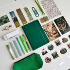 Collection of stationery items including pens, a notebook, and decorative stickers on a white surface.