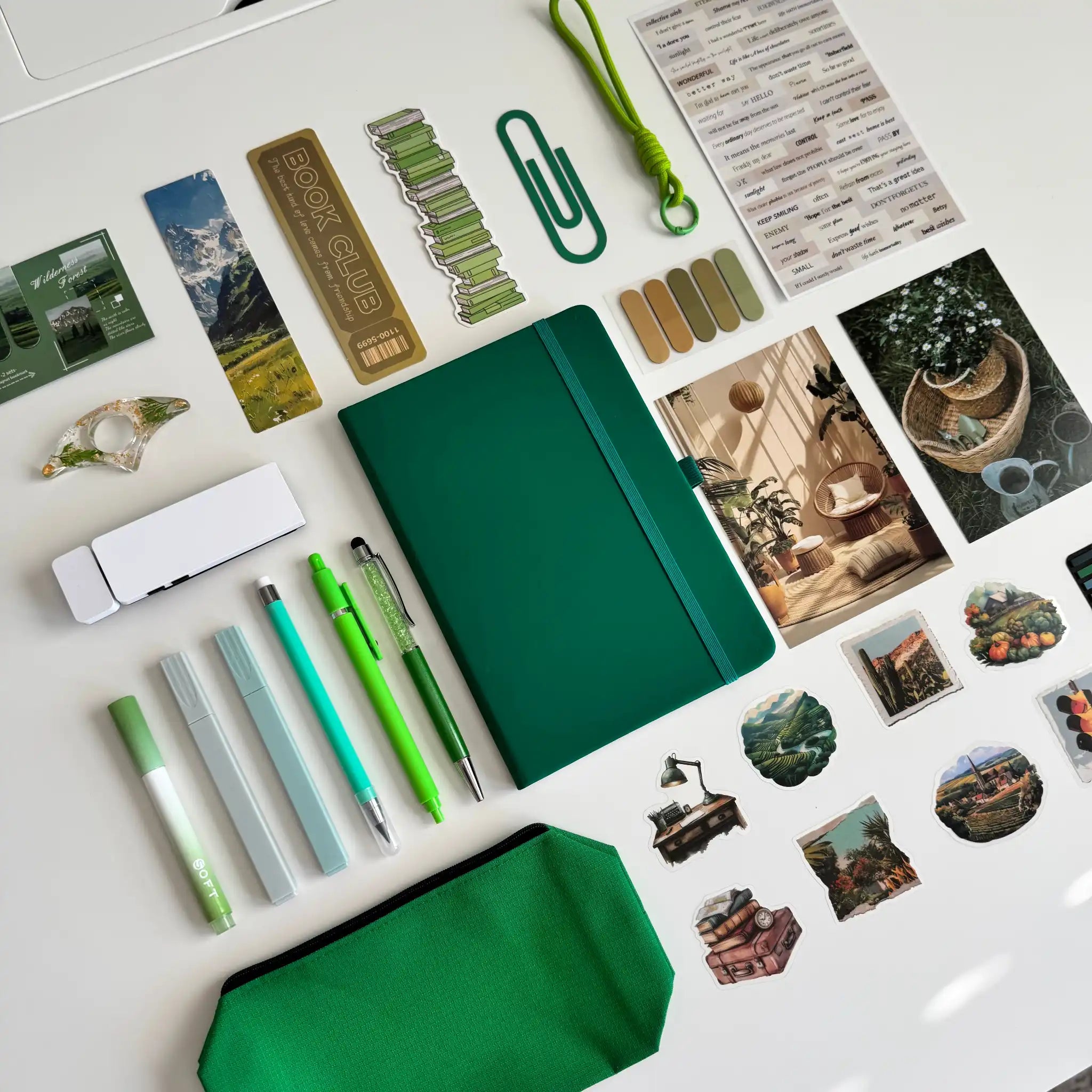Collection of stationery items including pens, a notebook, and decorative stickers on a white surface.