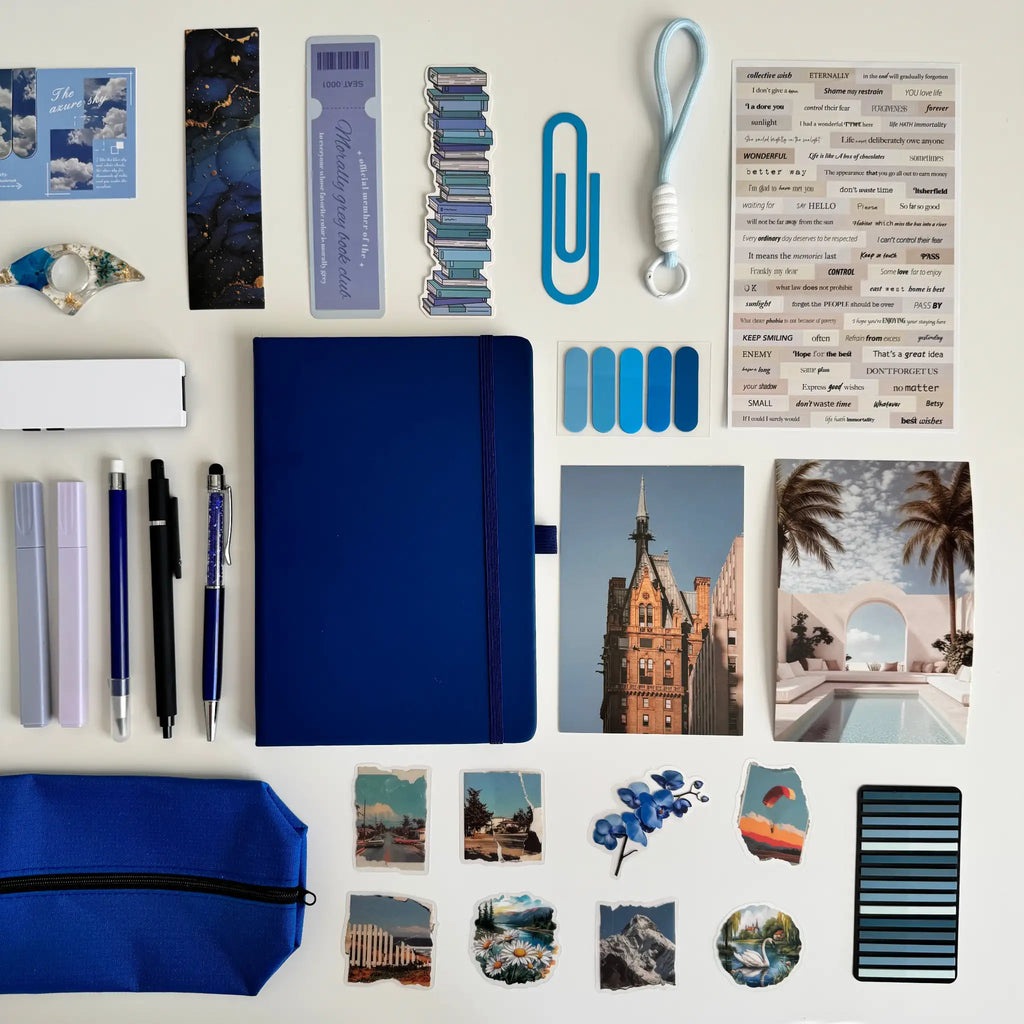 Collection of stationery items including a blue notebook, pens, and photo frames on a white background