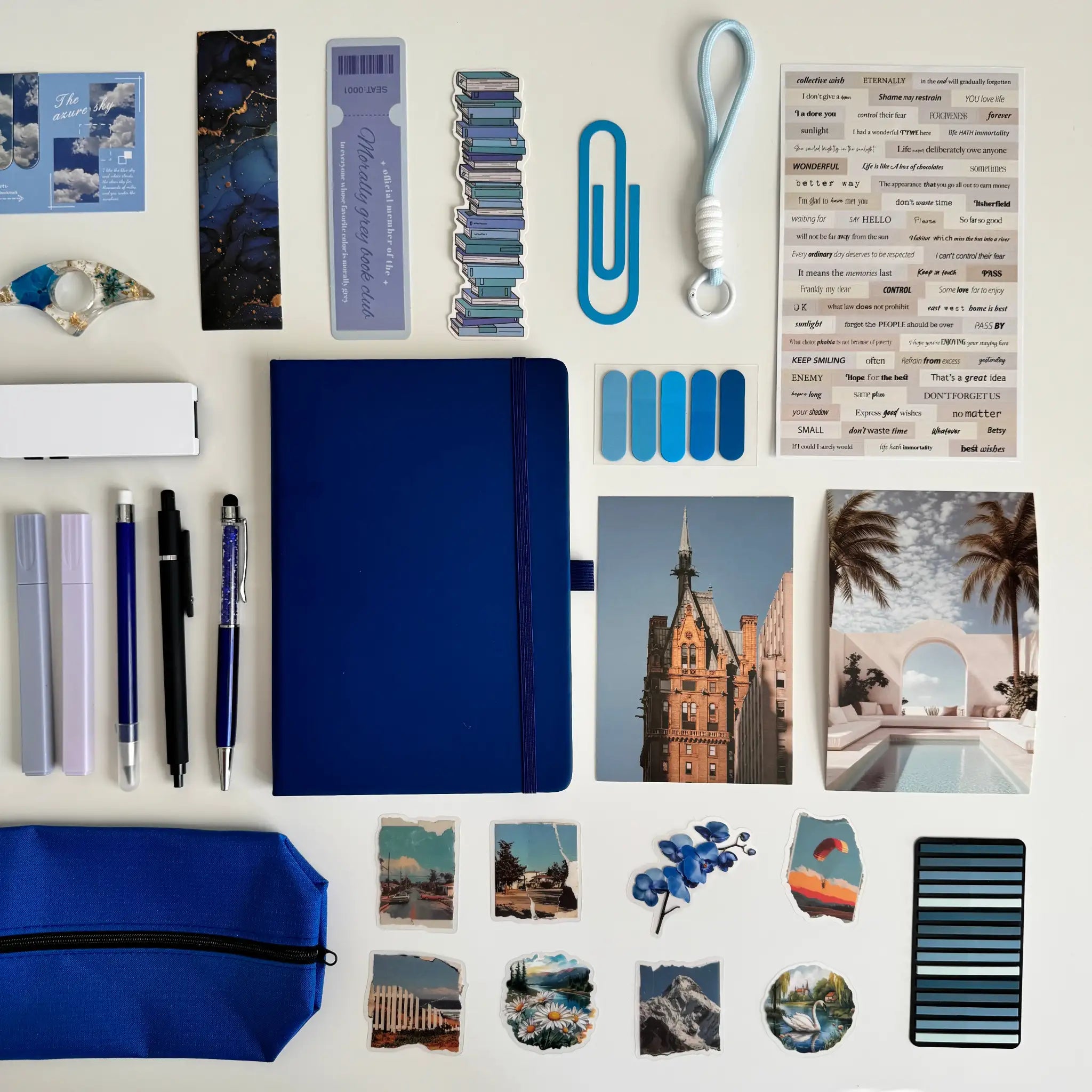 Collection of stationery items including a blue notebook, pens, and photo frames on a white background