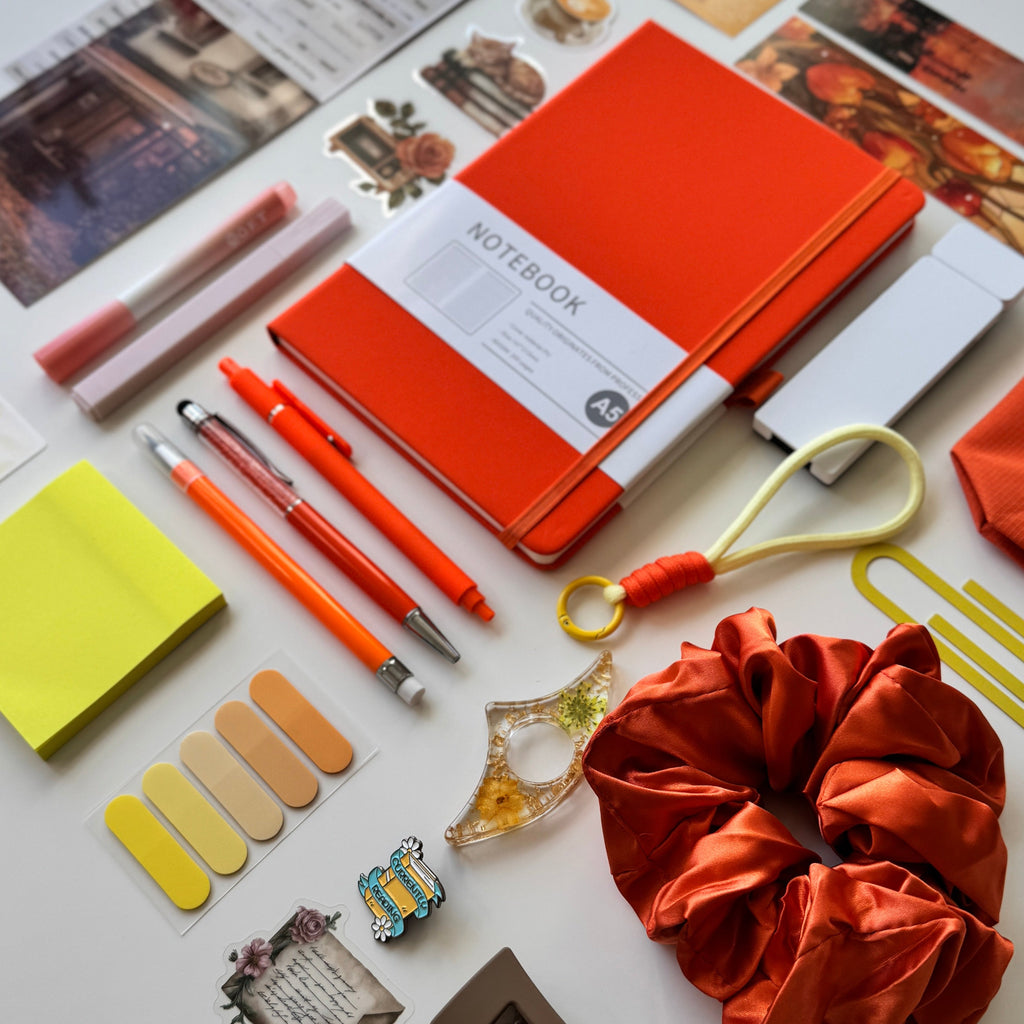 Collection of stationery items including notebooks, pens, and decorative objects on a white surface.