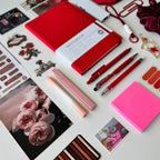Collection of stationery items including notebooks, pens, and photo frames on a white surface.