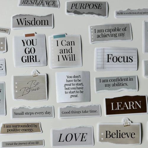 Motivational phrases on small cards attached to a white board.
