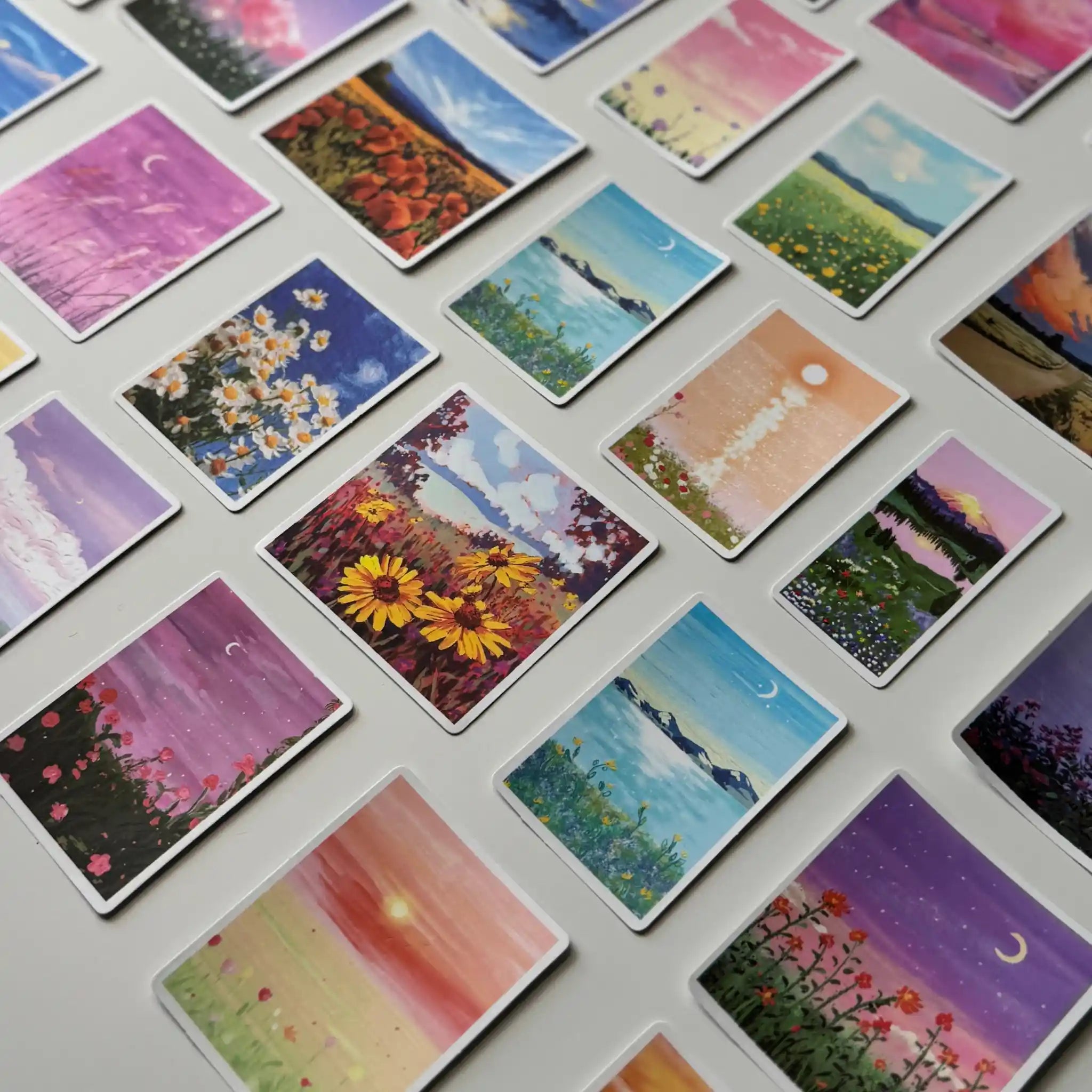 Collection of small cards with various scenic illustrations on a flat surface