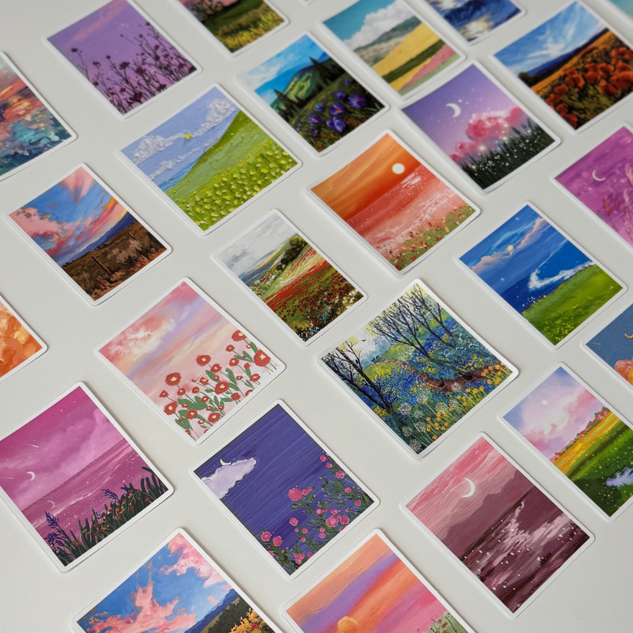 Collection of small painted cards with various landscapes on a white surface