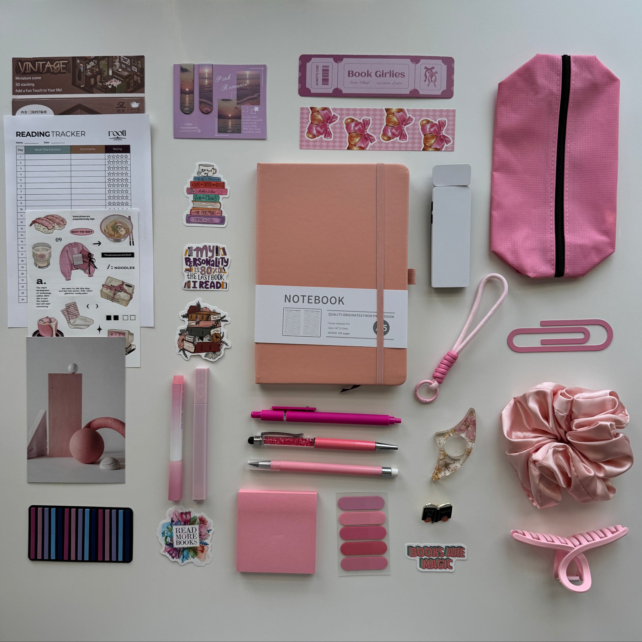 Collection of stationery items including a notebook, pens, and decorative stickers on a white surface.
