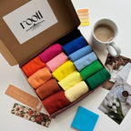 Box of colorful socks with a cup of coffee and stationery items on a table.