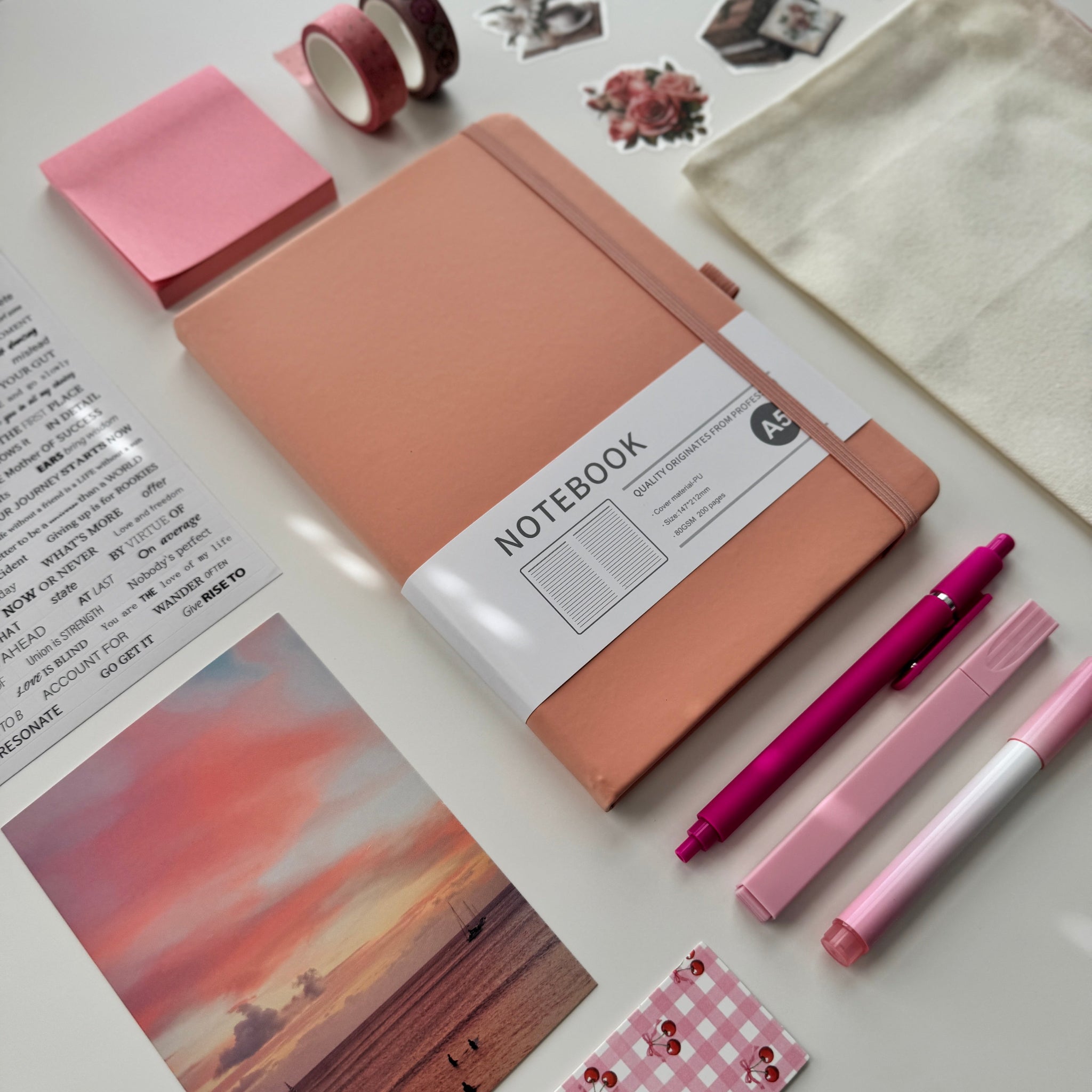 Pink notebook with stationery items on a light surface