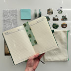 Open notebook with lined pages on a white surface with stationery items.