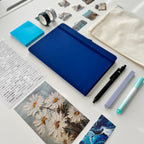 Blue tablet on a desk with stationery items and photos