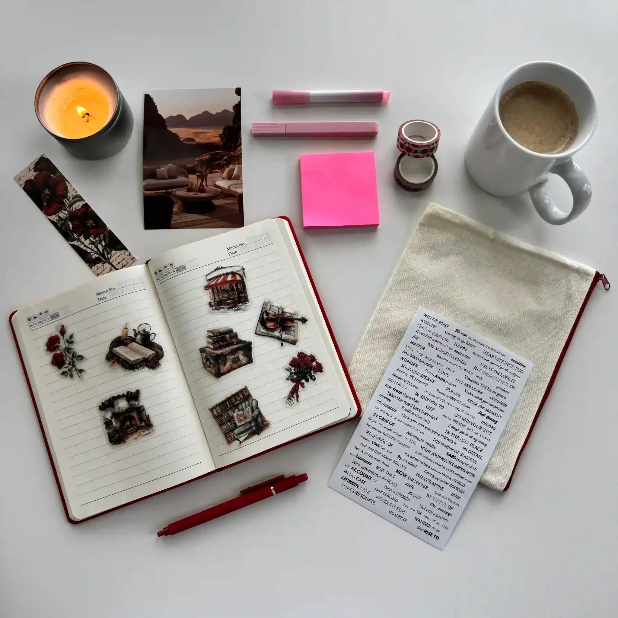 Open notebook with stickers, a cup of coffee, a candle, and stationery items on a white surface.