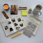Notebook with stickers, a pen, a mug, a candle, and other items on a white surface