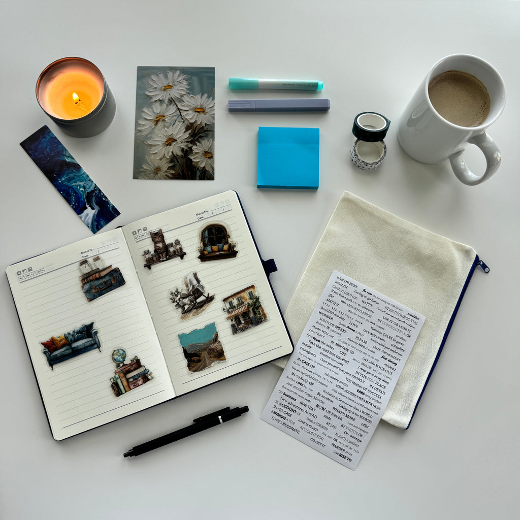 Desk setup with a notebook, coffee mug, candle, and stationery items on a white surface