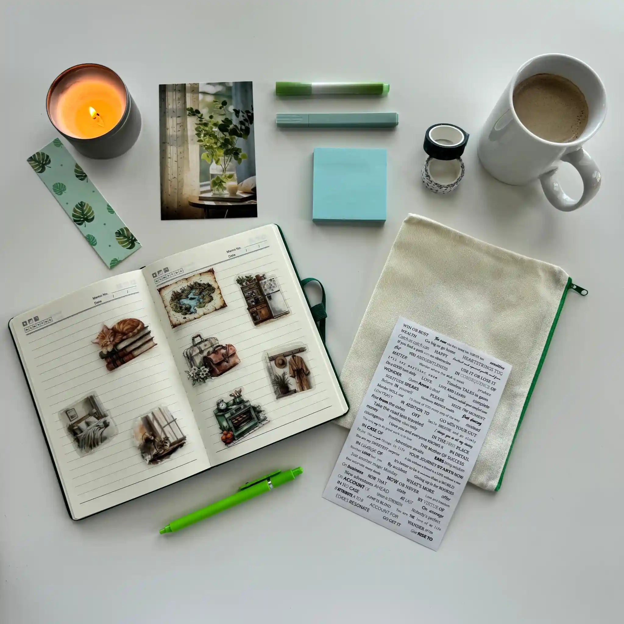 Desk setup with a notebook, mug, candle, and stationery items on a white surface