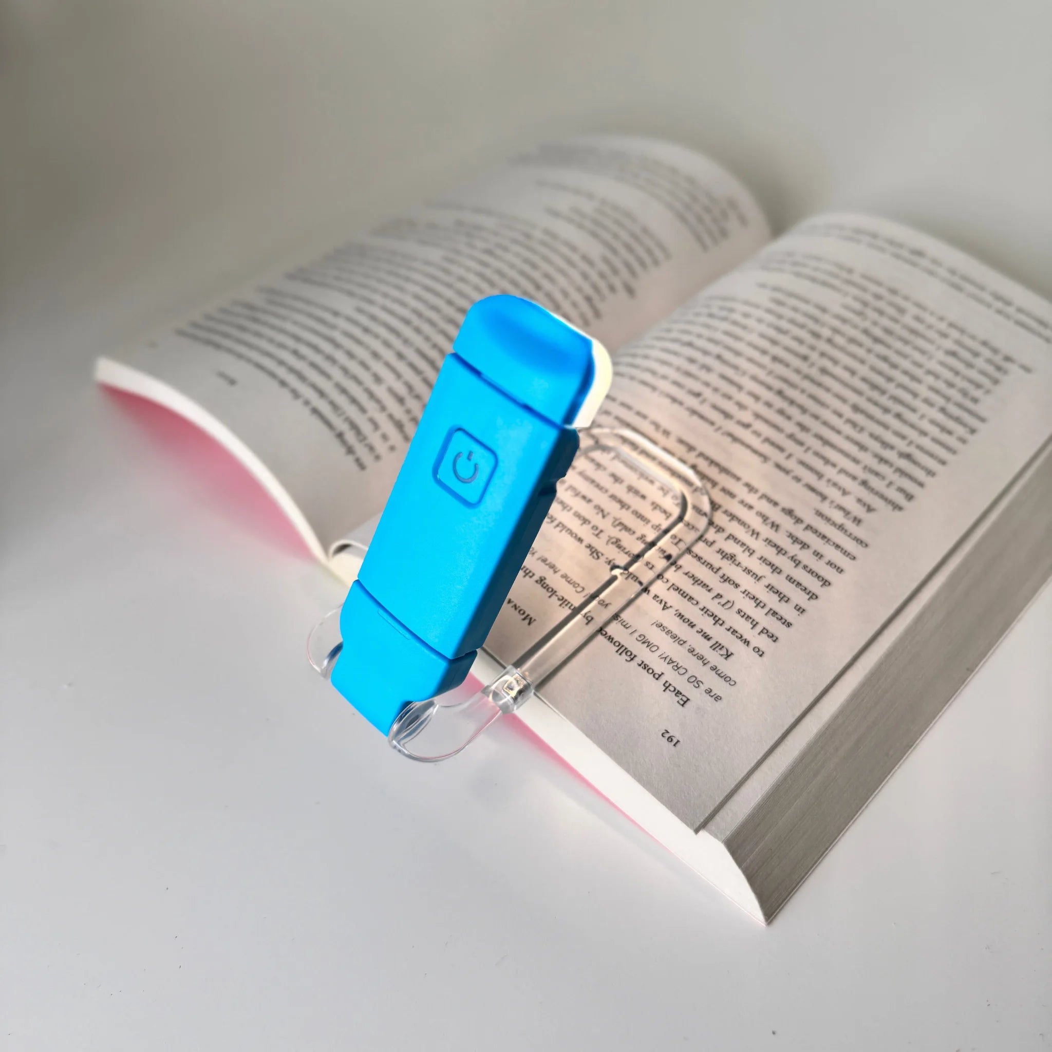 Blue booklight on an open book with a white background