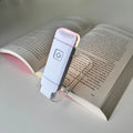 Reading lamp attached to an open book on a light gray background