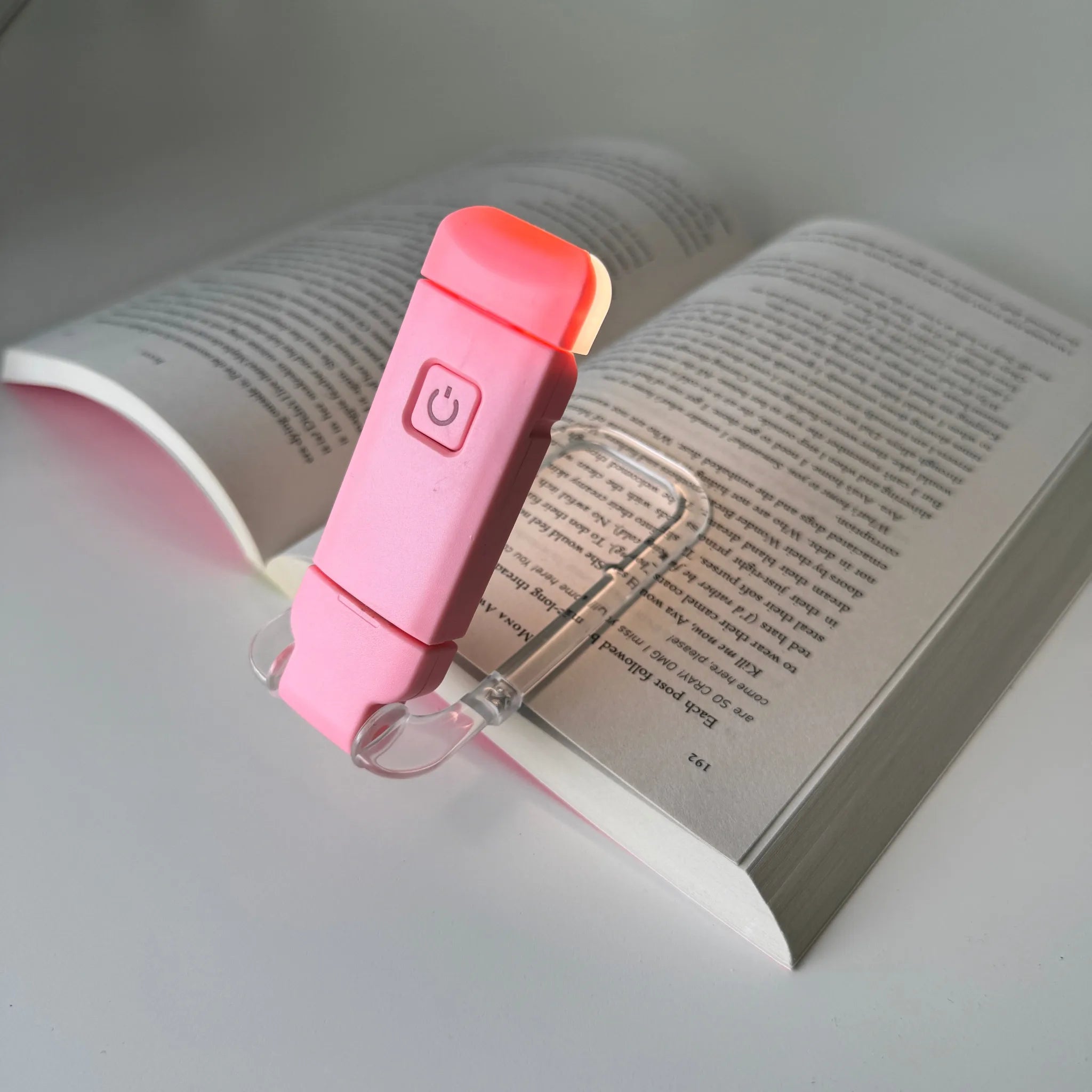Pink book light on an open book with a white background