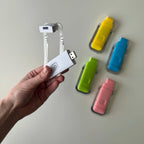 Hand holding a white USB reading light with colorful USB reading lights on a light gray background
