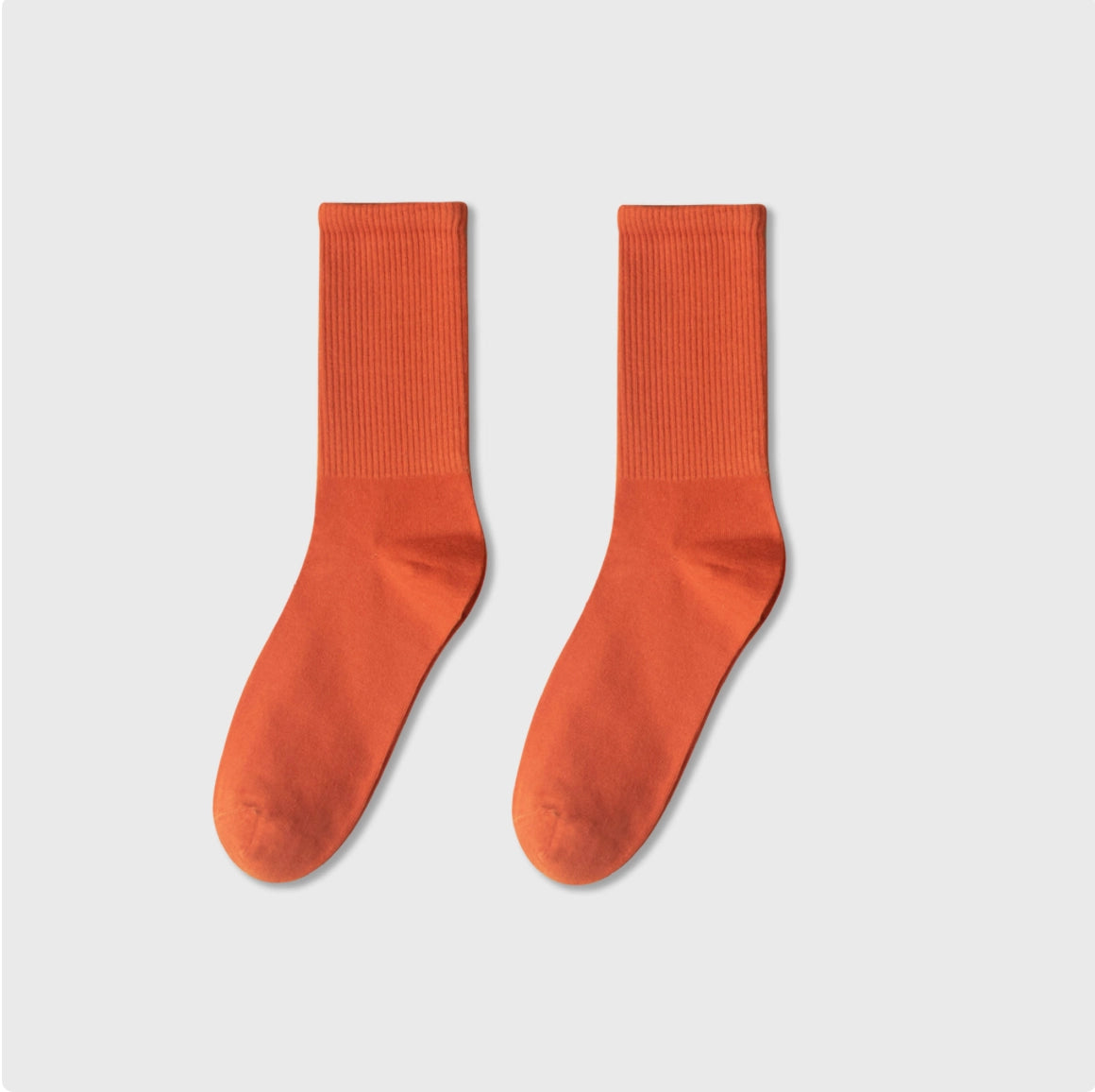 Pair of orange socks on a light gray background